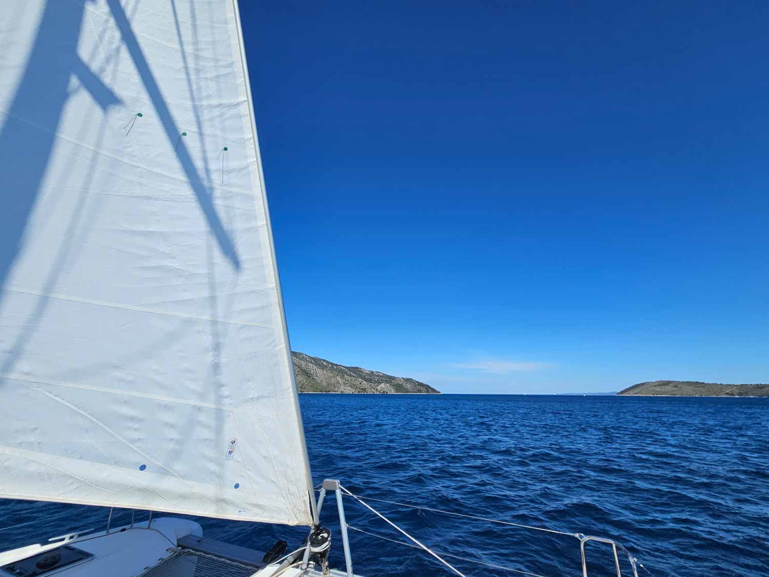 View past one of the sailts ot the deep blue sea and islands in the Adriatic during a Croatia sailing holiday with kids