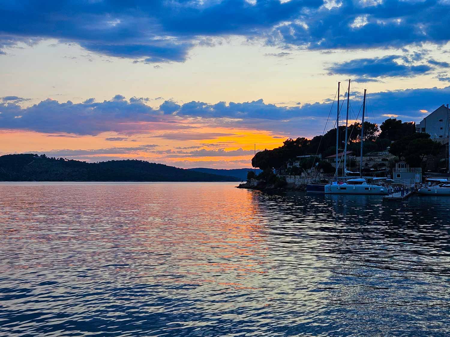 Headland and boat against the sunset at Milna on Brac, the first stop on our Croatia sailing holiday with kids