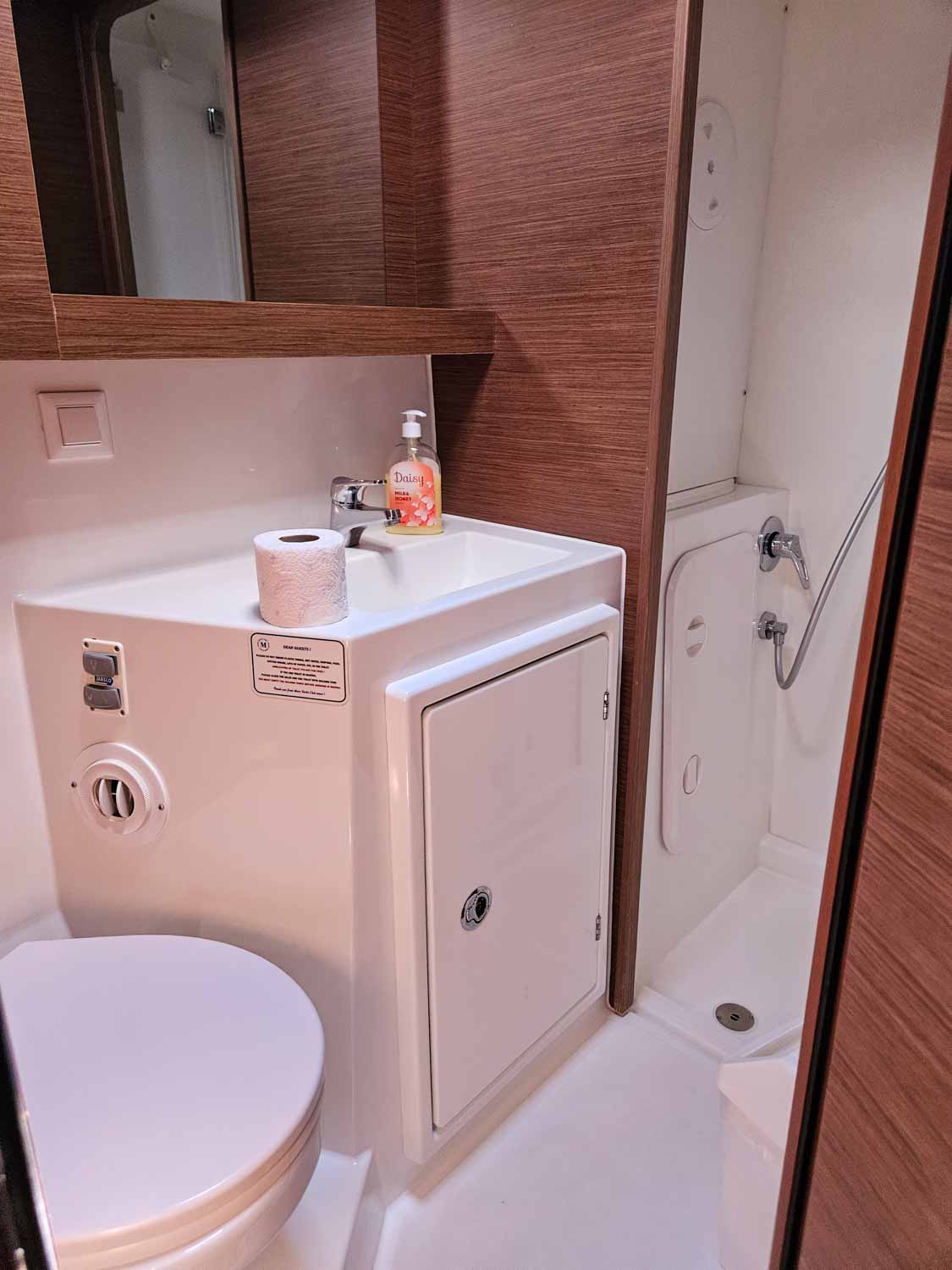 View of the small ensuite bathroom with toilet, sink and shower, plus storage space, in our cabin aboard our Lagoon 42 catamaran - my review of a More Sailing Croatia holiday with kids