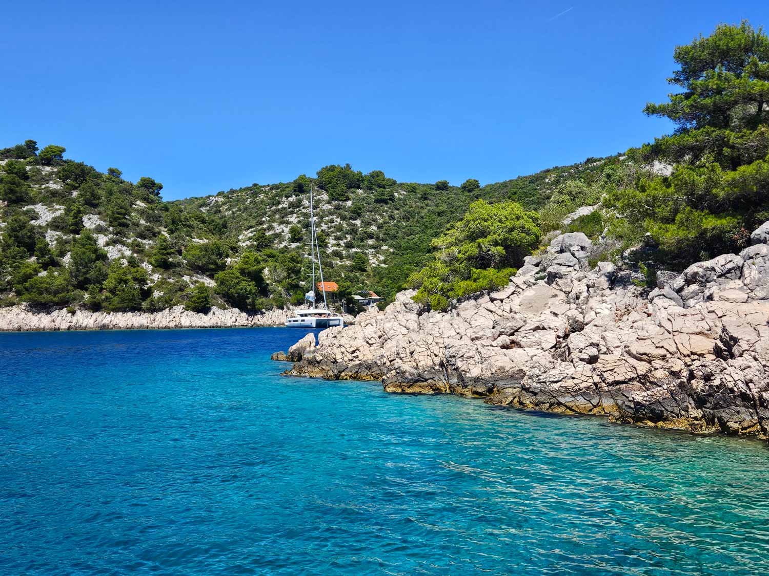 View of a boat moored around the rocks in one of the little bays on Solta where we stopped during a Croatia sailing holiday with kids