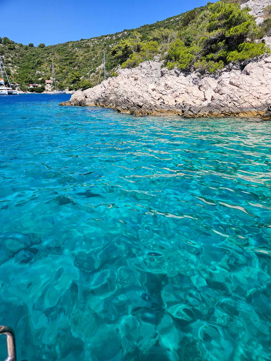 View of clear turquoise water in one of the little bays on Solta during a Croatia sailing holiday with kids
