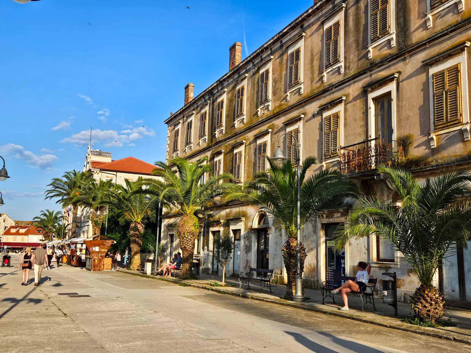 View of palm trees and buildings along the waterfront at Stari Grad on Hvar, one of the stops on a Croatia sailing holiday with kids