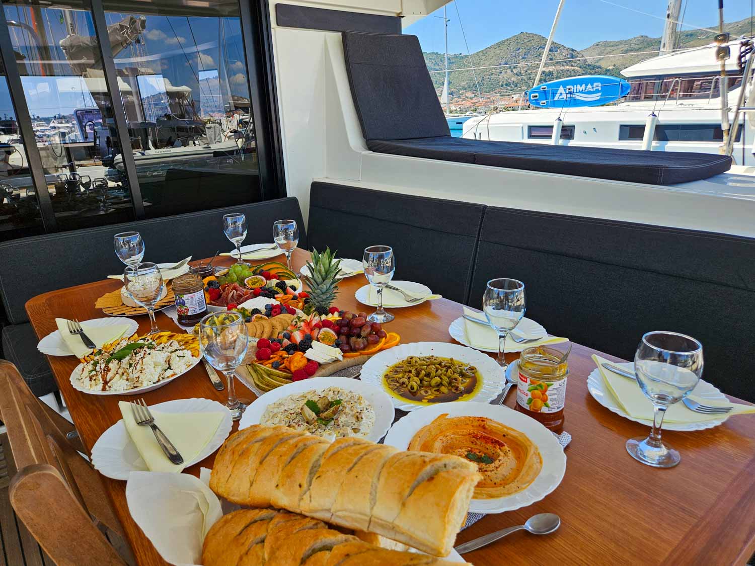 View of welcome dishes of food on the table aboard our Lagoon 42 catamaran, including bread, dips, salads and fruit - my review of a More Sailing Croatia holiday with kids