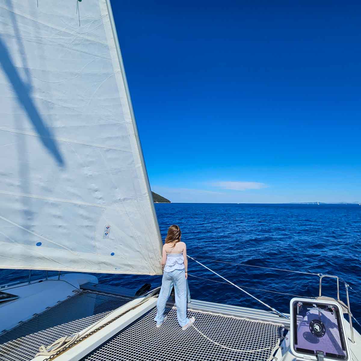 View of my daughter standing on the nets at the front of our Lagoon 42 catamaran during a More Sailing Croatia holiday - my review of a Croatia sailing holiday with kids