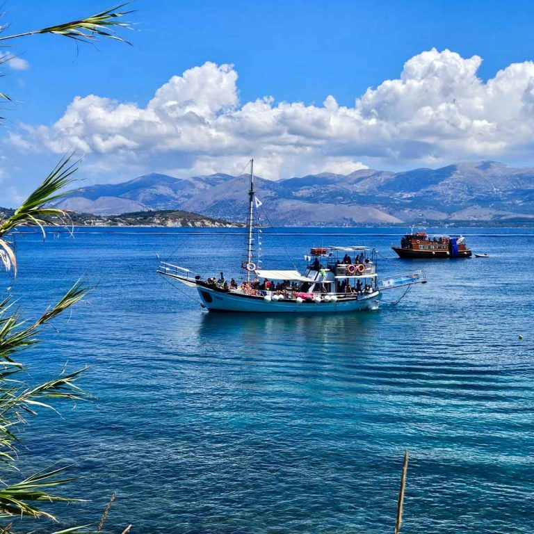 View of several boats moored off Vardiani Island - one of the most popular stops on a Kefalonia boat trip with kids