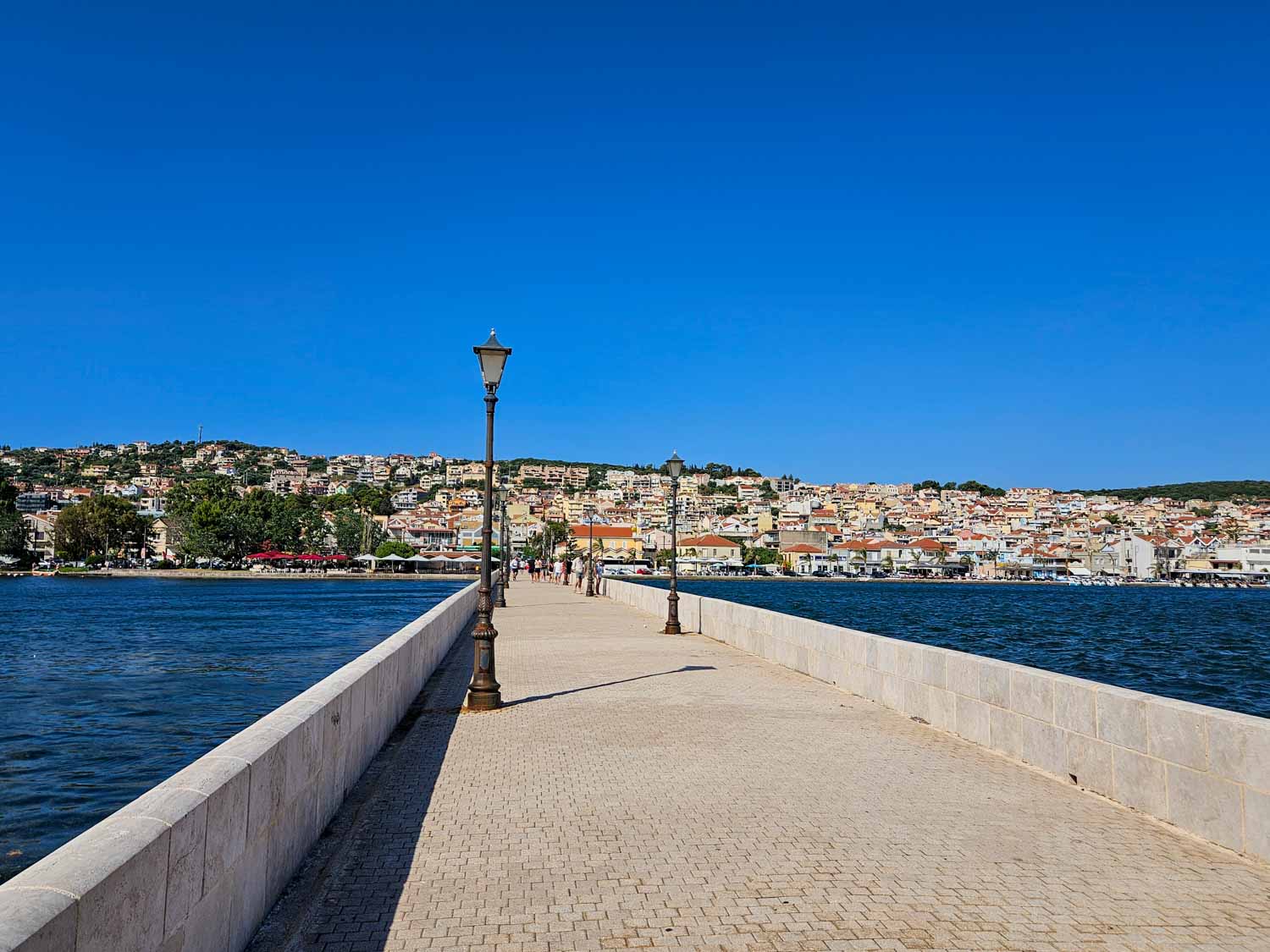 View of De Bosset Bridge with the lagoon and colourful town buildings visible beyond - one of the best things to do in Argostoli with kids