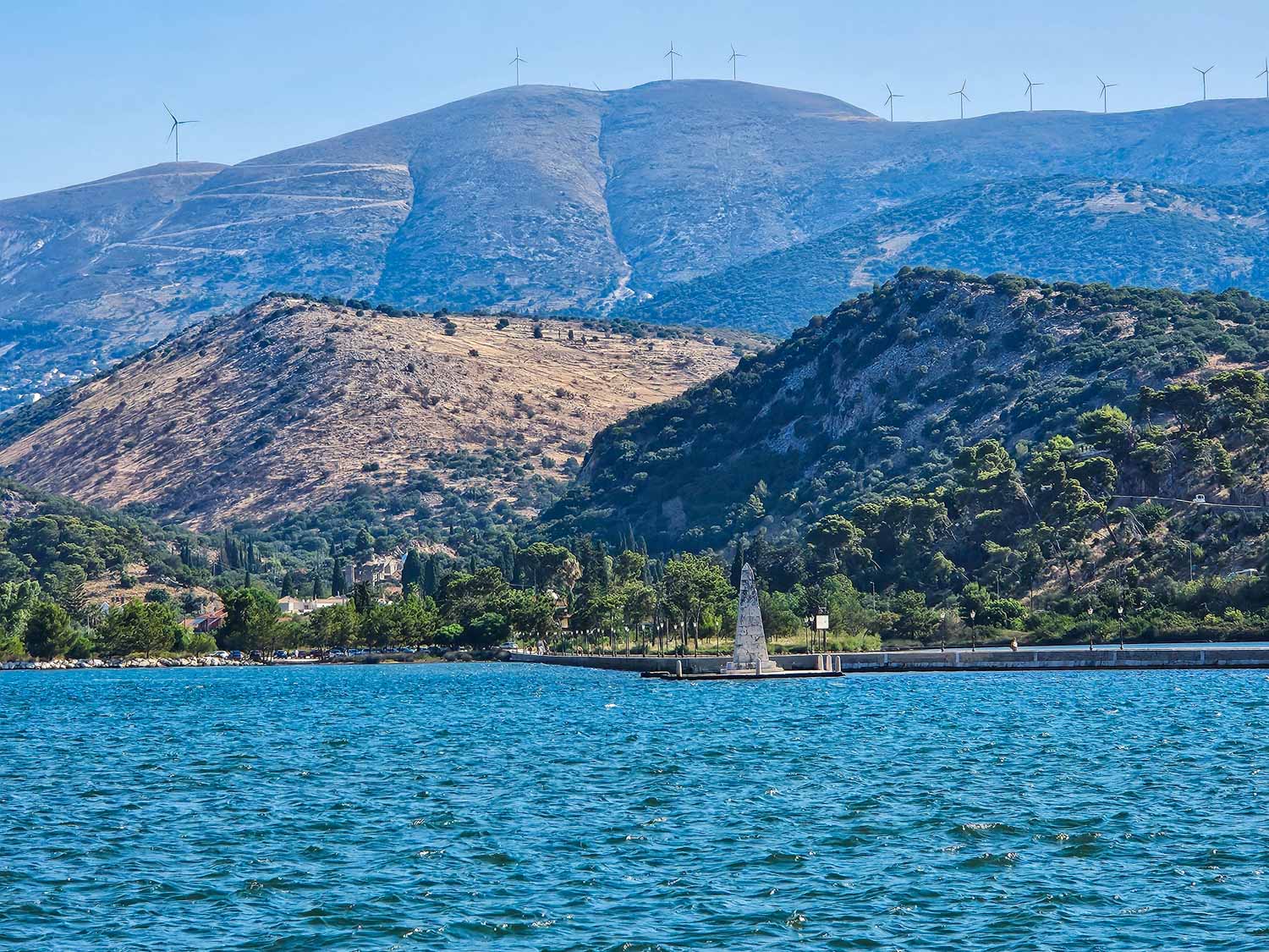 View across the lagoon to the obelisk and De Bosset bridge with the hills visible beyond - walking the bridge is one of the best things to do in Argostoli for families