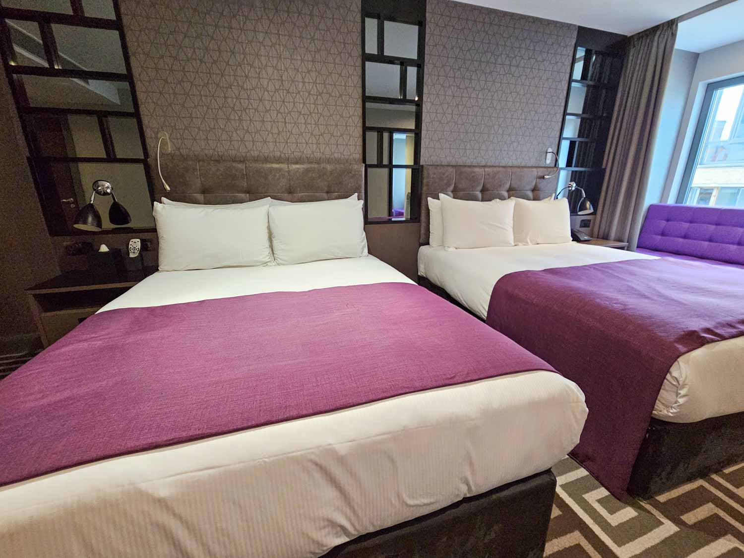 Two double beds with purple accents, and bedside tables in our Hoxton family suite - my Courthouse Hotel Shoreditch review