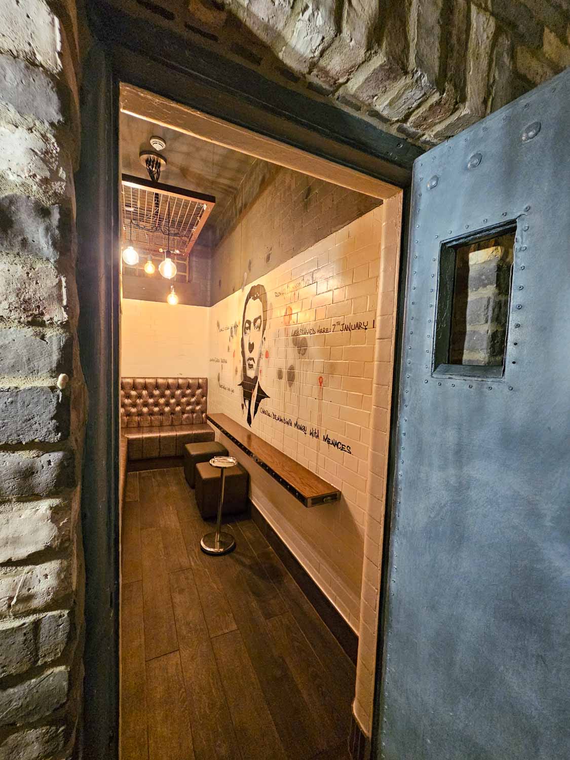 View of one of the converted prison cells in the Jailhouse bar with a painting of one of the Kray twins on the wall - my Courthouse Hotel Shoreditch review