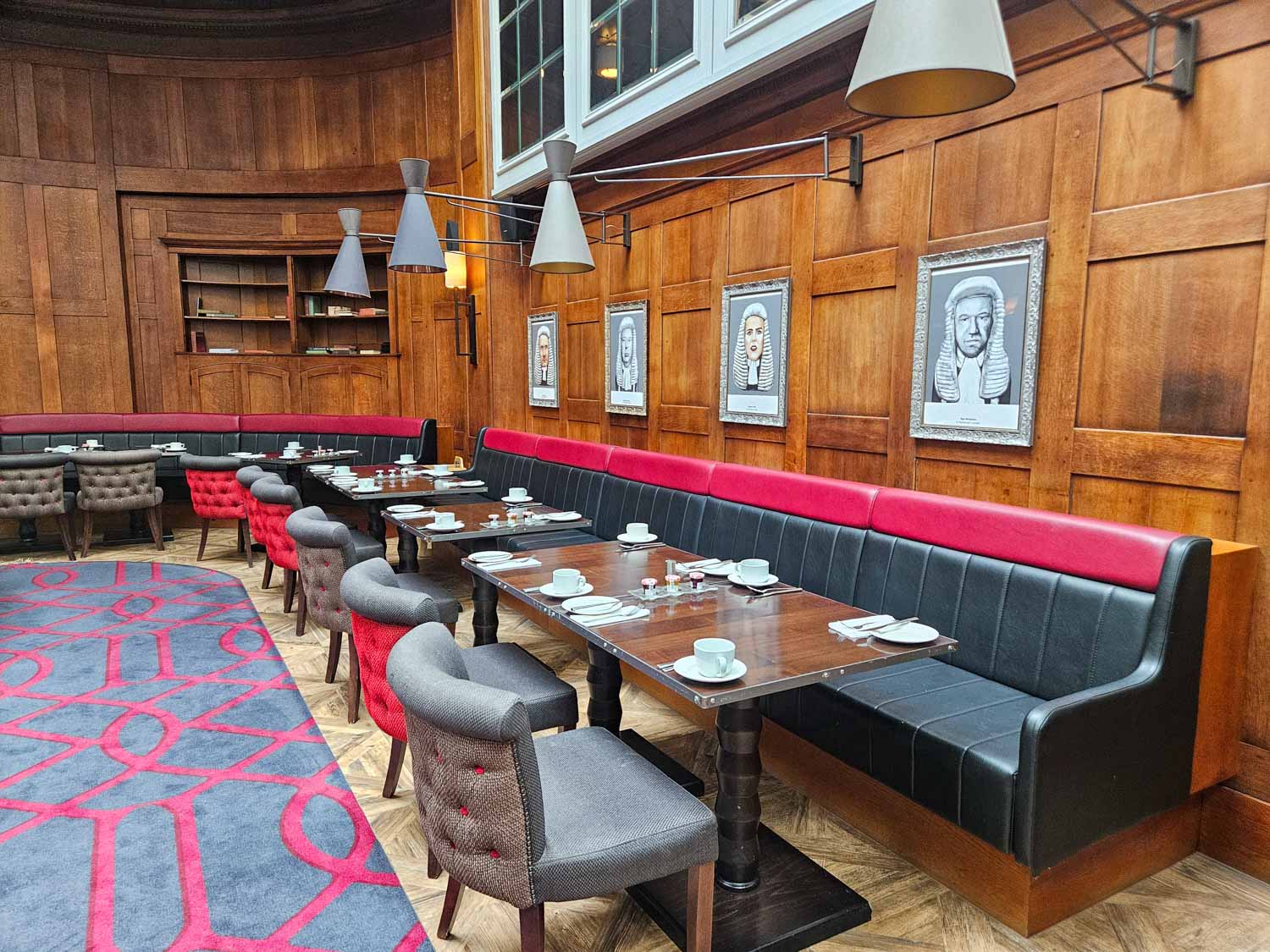 View of tables in the Judge and Jury restaurant inside the old courtroom 2, with portraits of Londoners on the walls - my Courthouse Hotel Shoreditch review