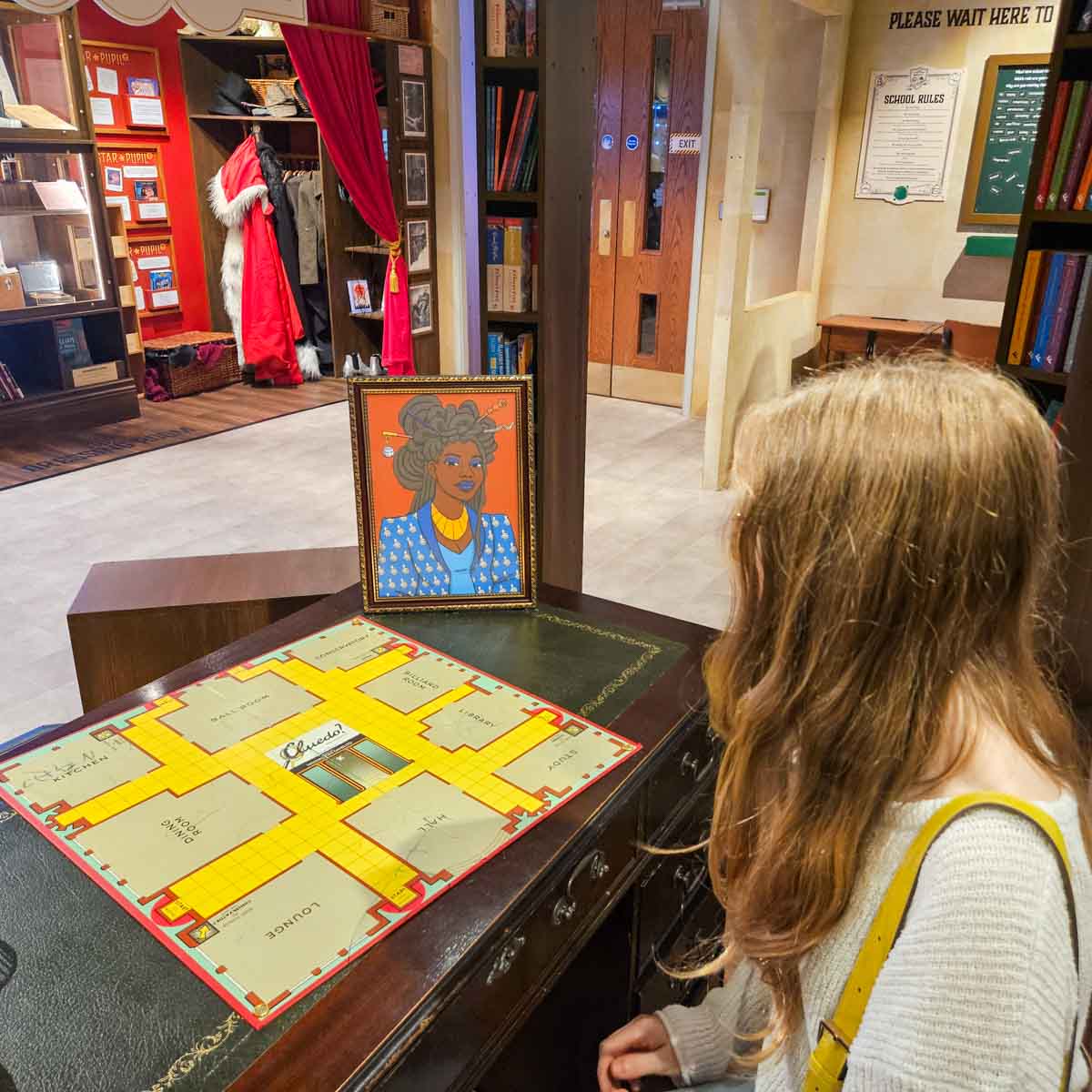 My daughter looks at a Cluedo board and portrait of missing Mystery Academy head teacher at the new Oxford Story Museum exhibition - my Mystery Academy review