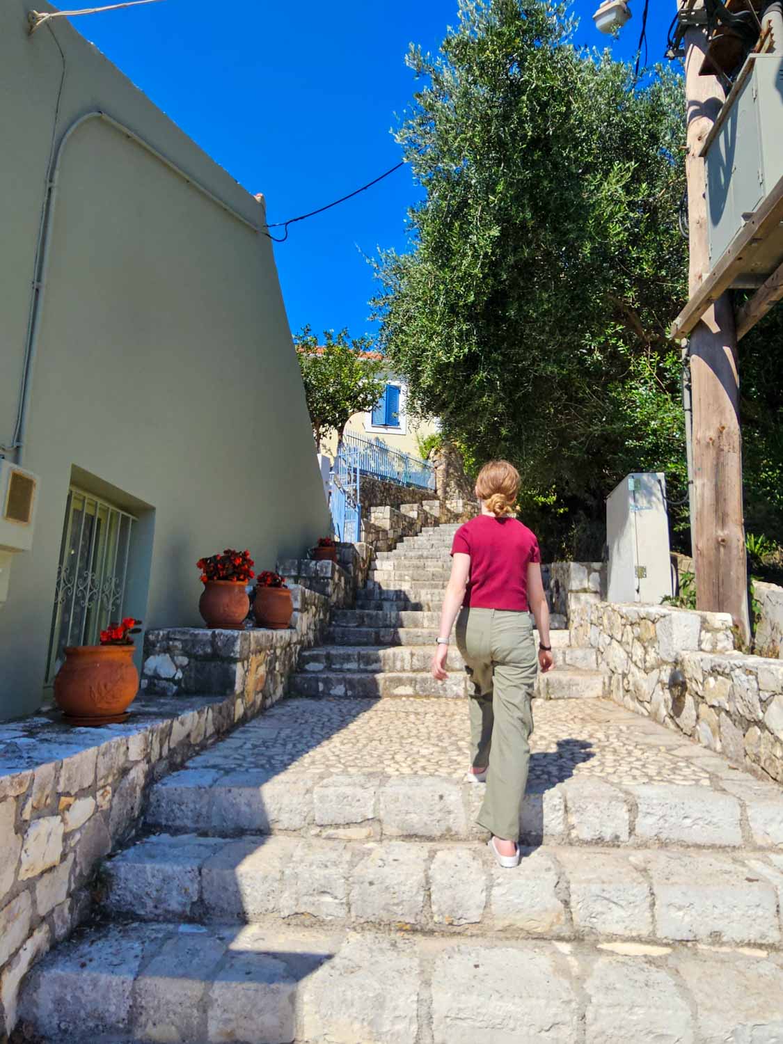 My daughter climbs stone steps lined with pots full of colourful flowers - what to do during one day in Fiskardo with kids