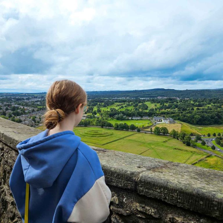 My daughter looks out from the castle walls over the gardens to the countryside around Stirling - my tips for the best things to do in Stirling with kids