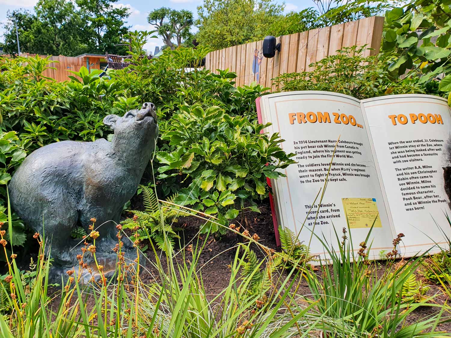 Statue at London Zoo of a bear with a book reading 'from zoo to Pooh' about the black bear which inspired Winnie the Pooh - there's a new trail marking the story's anniversary during October half-term in London for families