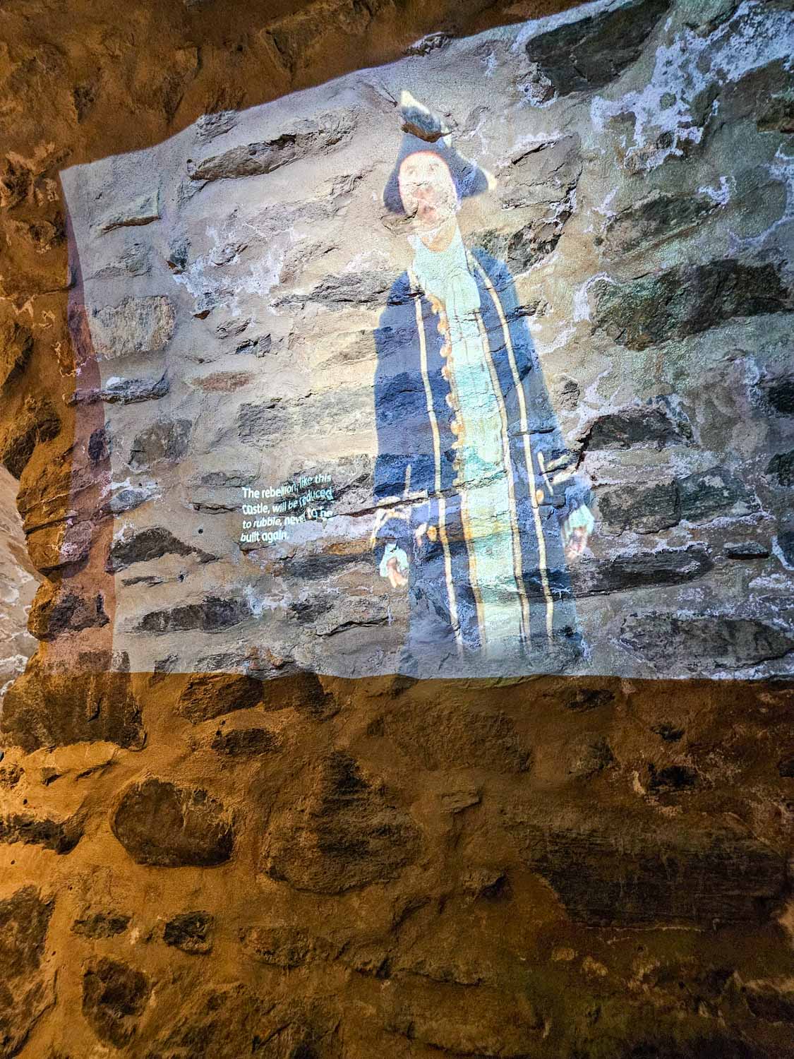 Video projected on a wall of Eilean Donan Castle narrating the siege of 1719 - a visit is an easy day trip from the Isle of Skye with kids