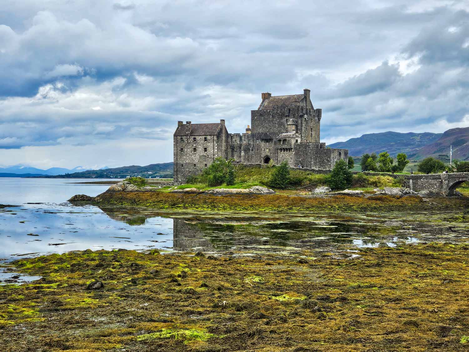 View of Eilean Donan Castle on a loch at the end of a stone bridge - a visit is an easy day trip from the Isle of Skye with kids