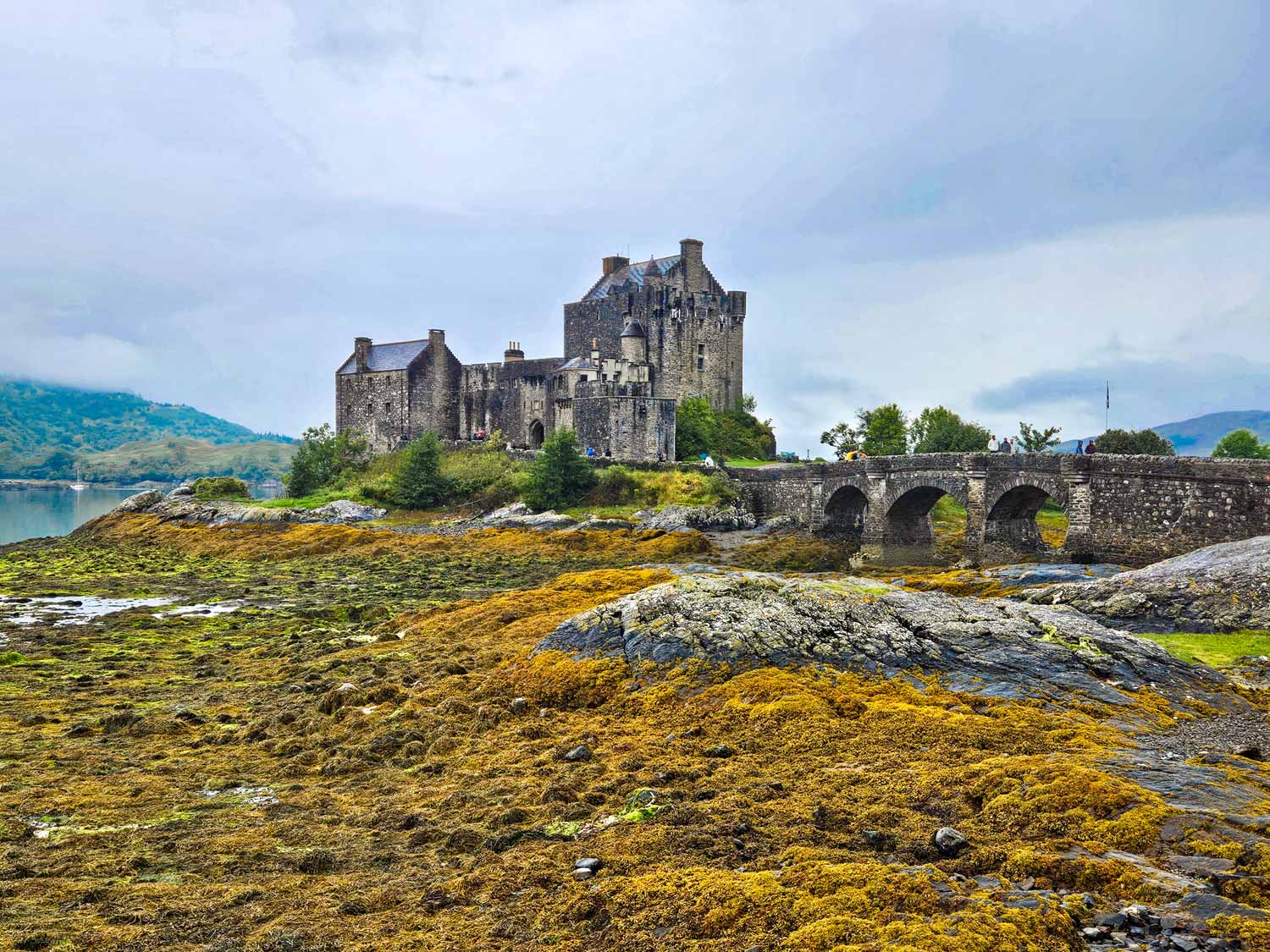 View of Eilean Donan Castle and its stone bridge on a cloudy day - a visit is an easy day trip from the Isle of Skye with kids