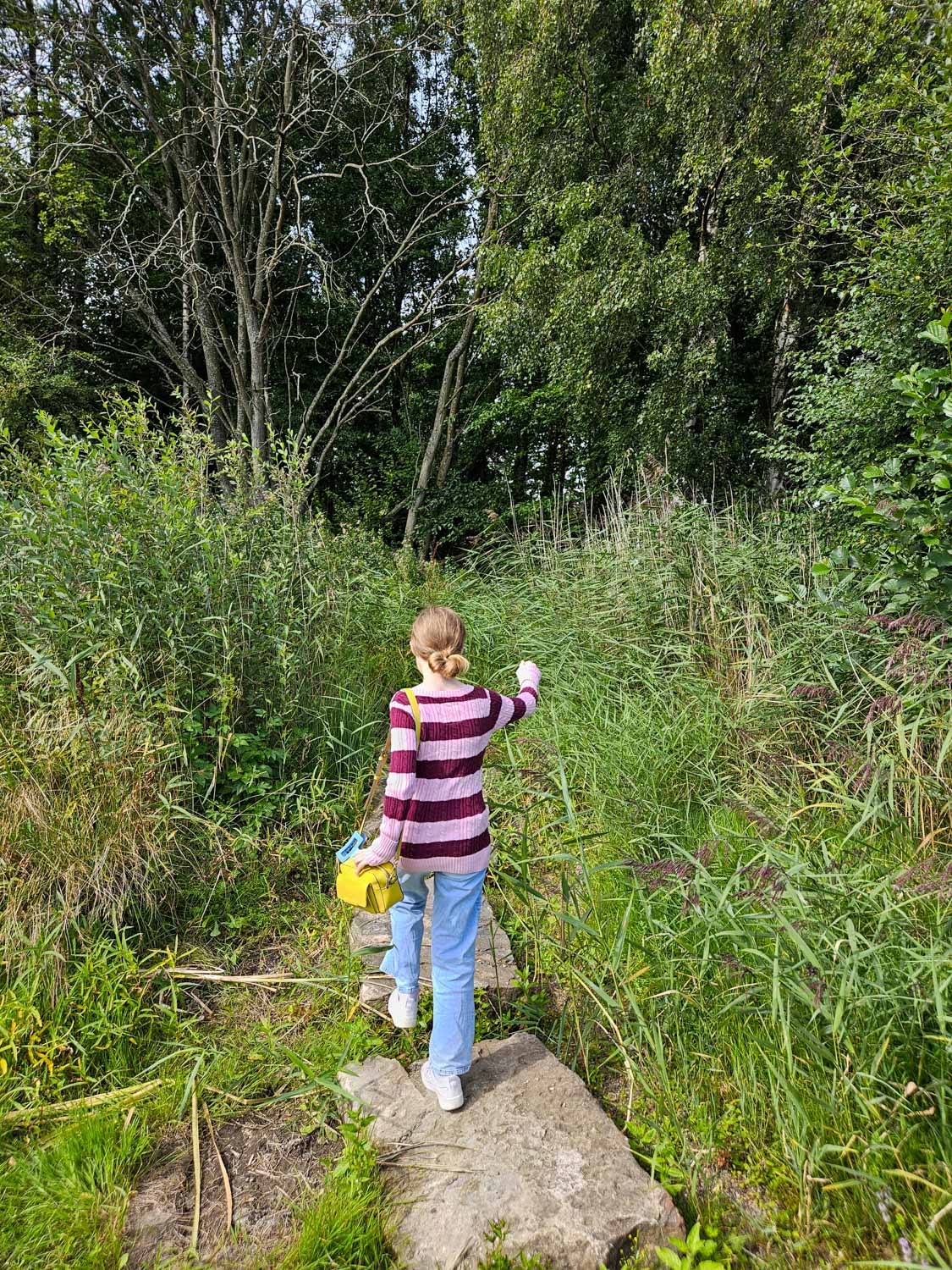 My daughter walks along stepping stones towards the trees at Helix Park - my pick of the best things to do in Falkirk with kids