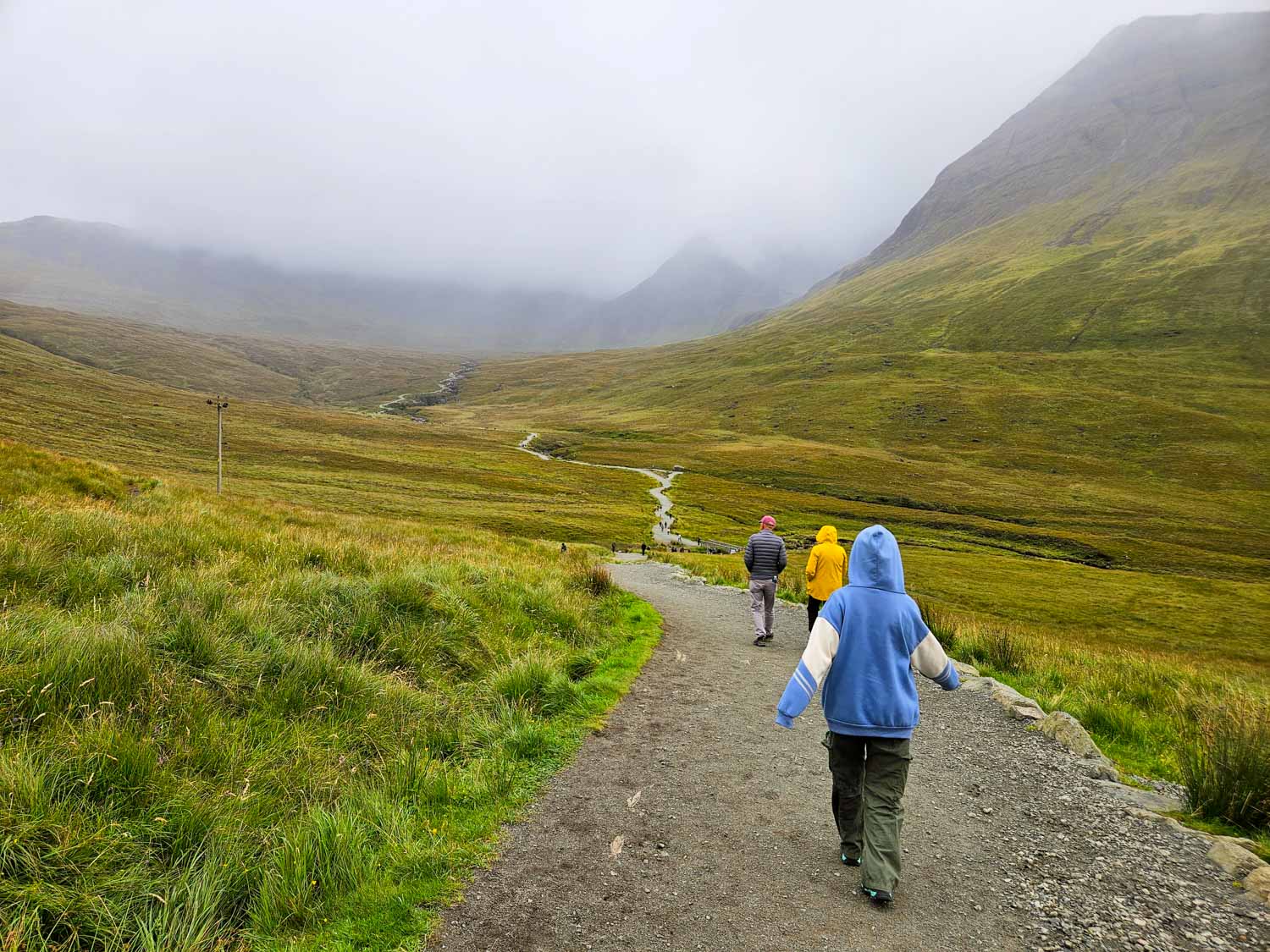 My daughter walks down towards the valley and the Fairy Pools on a misty day - a visit is one of the best things to do in the Isle of Skye with kids