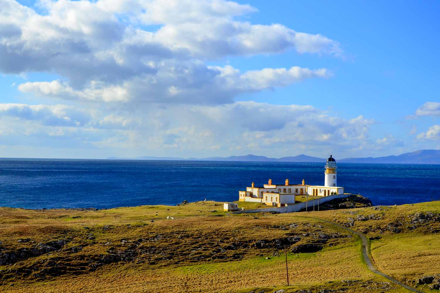 View of the lighthouse at Neist Point with the dark blue sea and sky behind - one of the places to visit on the Isle of Skye with kids