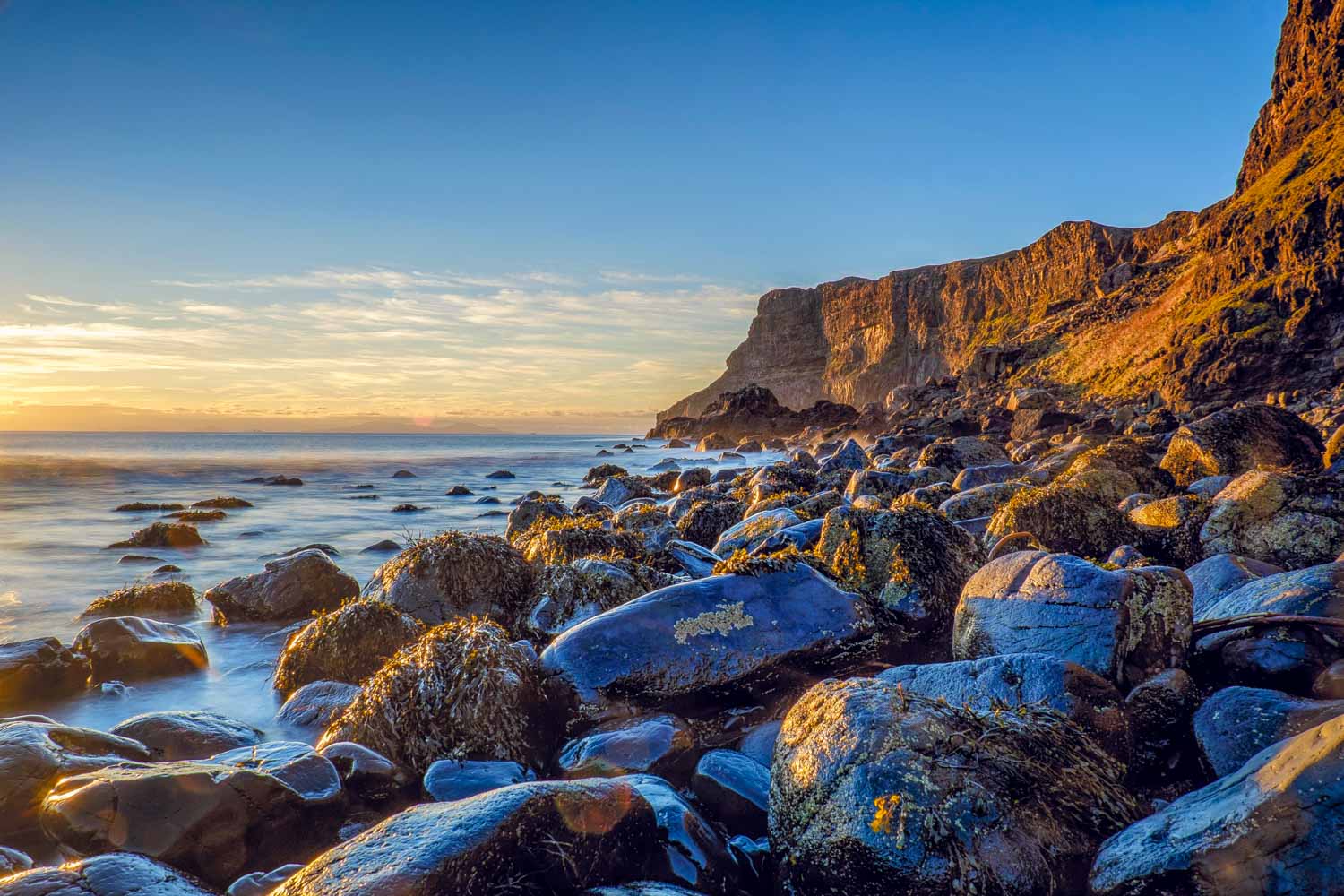 View across the black stones and rocks of Talisker Beach with the cliffs in the background - a visit is one of the best things to do in the Isle of Skye with kids