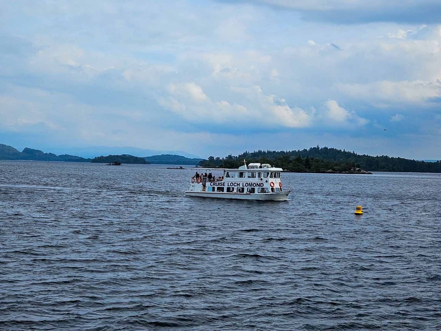 White boat from Cruise Loch Lomond out on the water - one of the great things to do during a Scotland road trip with kids