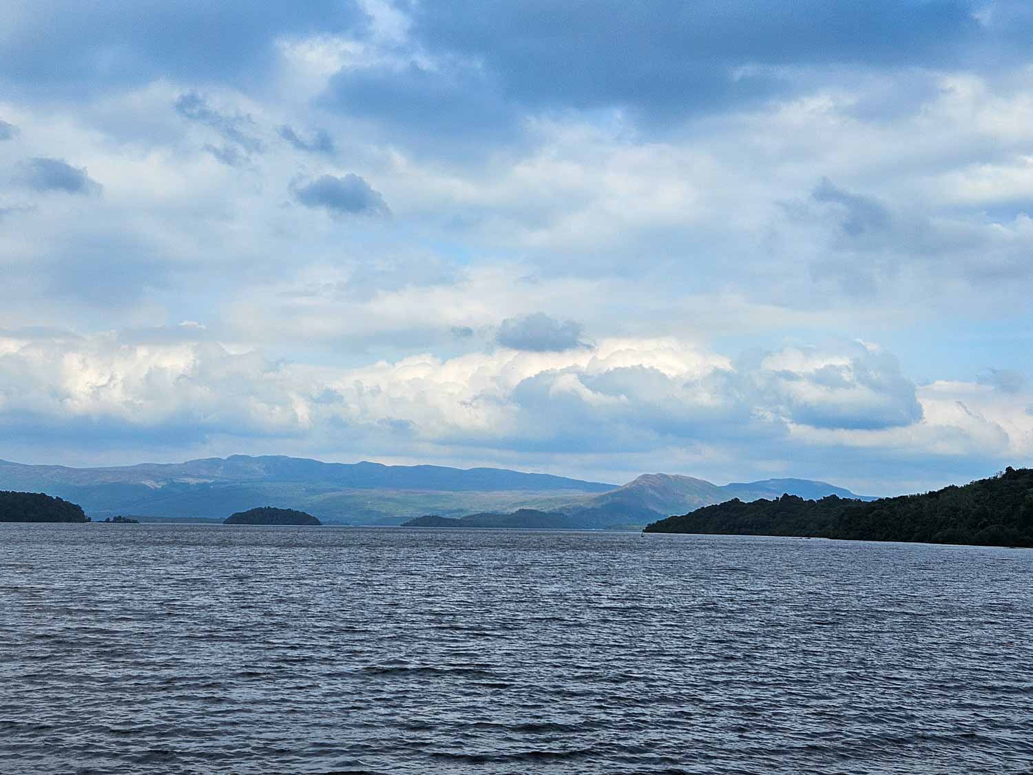 View across the water to some of the little islands and hills in the background - a boat trip is one of the best things to do in Loch Lomond with kids