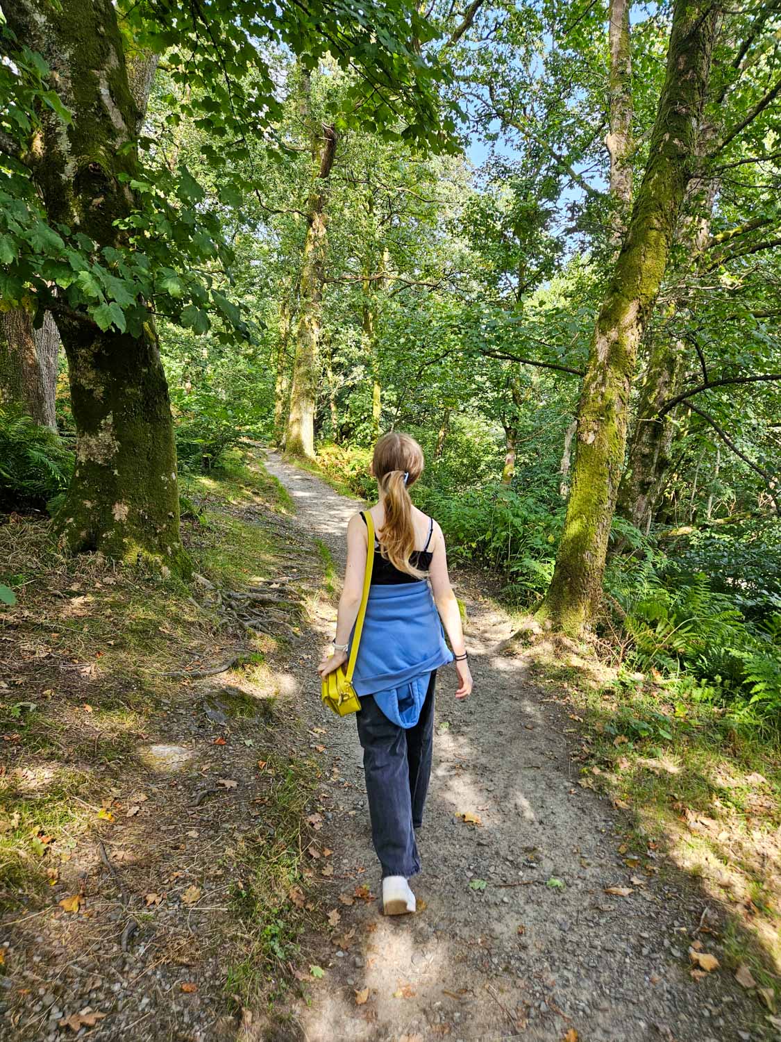 My daughter walks on a path through woodland near Luss - my pick of the best things to do in Loch Lomond with kids