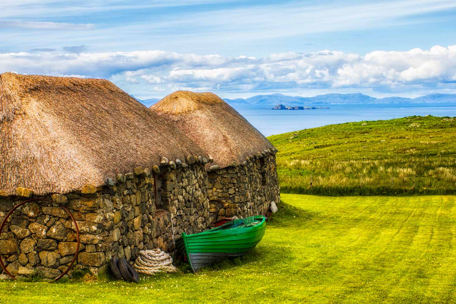 Thatched crofter houses at the Skye Museum of Island Life with the grass and sea behind - a visit is one of the fun things to do on the Isle of Skye with kids