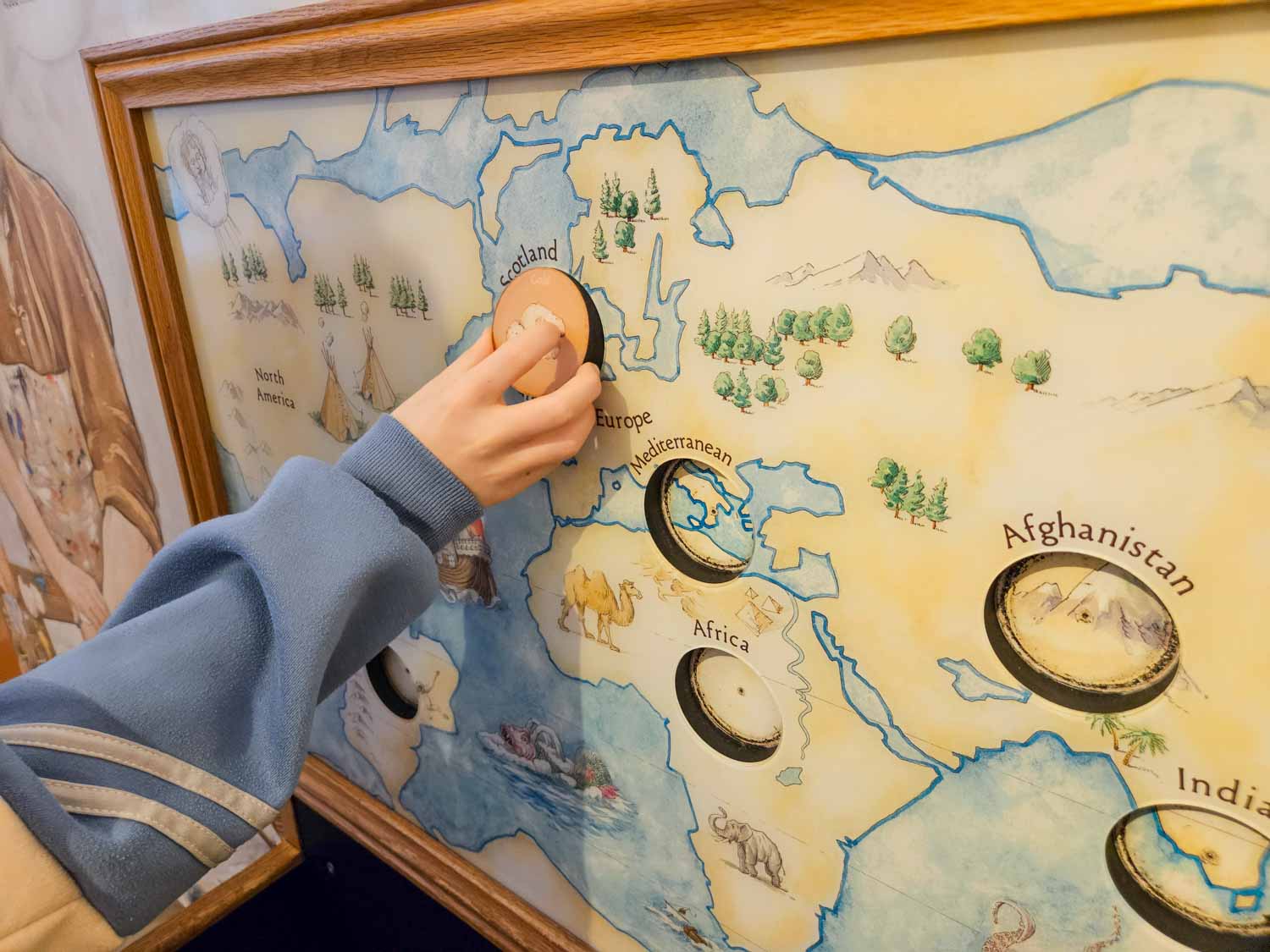 My daughter slots a piece into a puzzle about medieval trade in the castle vaults - a visit to Stirling castle is one of the best things to do in Stirling with kids