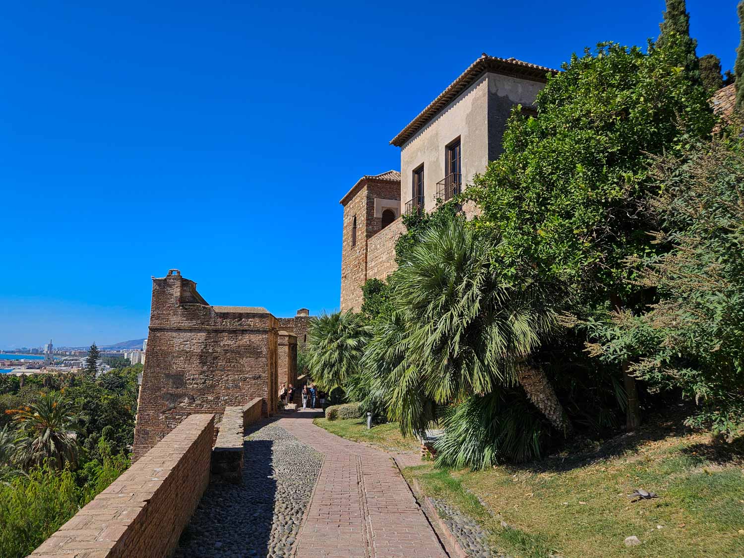 View along the path into the Alcazaba, now lined with trees and Malaga just visible beyond - a visit is one of the best things to do in Malaga with kids