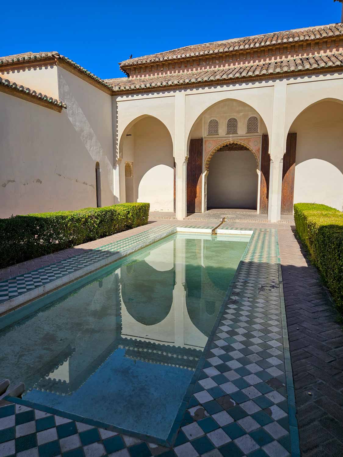 View of one of the courtyards with pool reflecting the palace buildings of the Alcazaba in Malaga - a visit is one of the best things to do in Malaga with kids