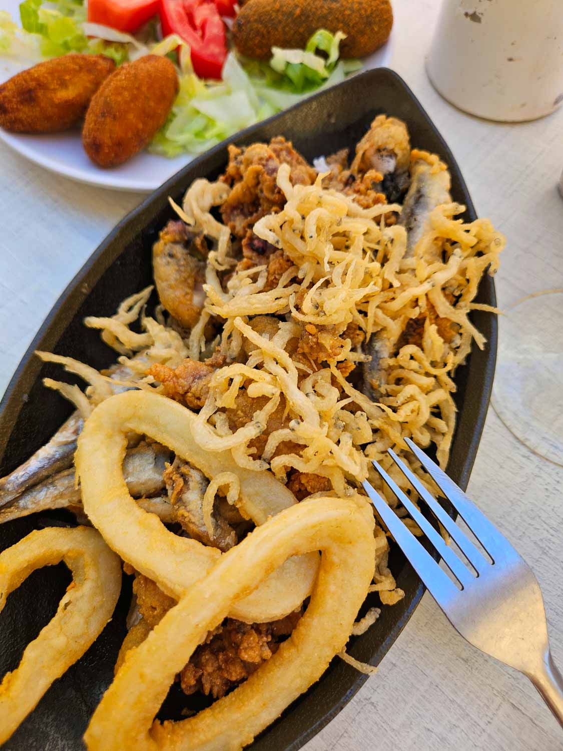 Plate with deep-fried fish and seafood and another with croquetas at one of the tapas bars around Atarazanas market in Malaga - a visit is one of the unmissable things to do in Malaga with kids