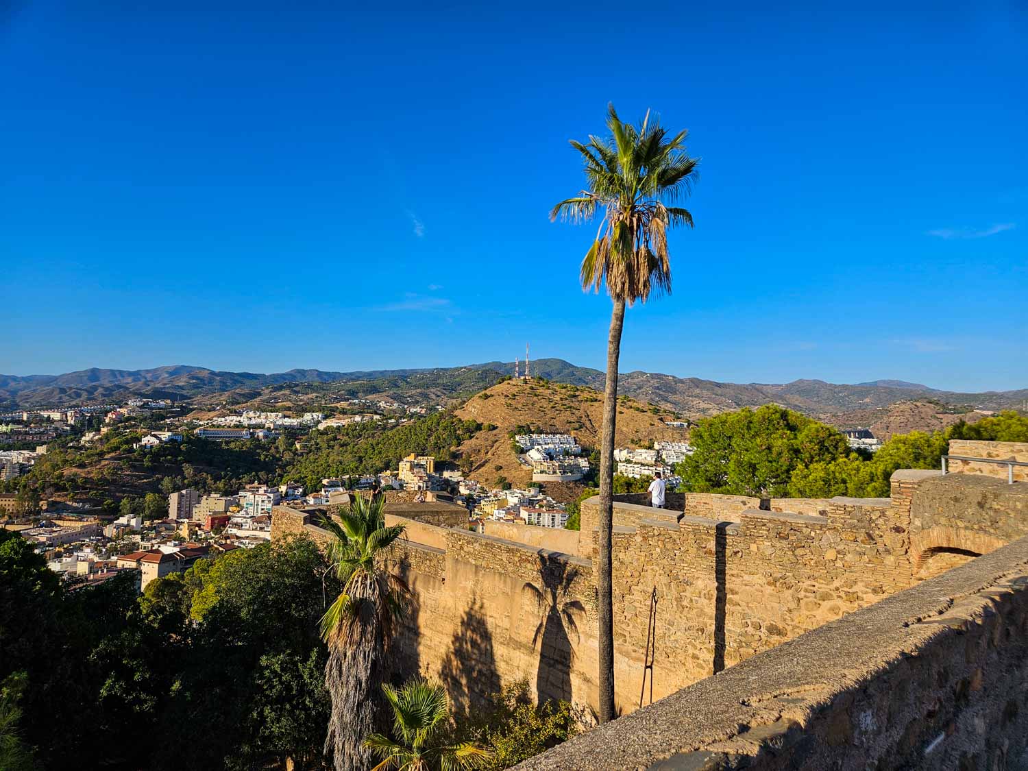 View of the walls and one of the towers of Gibralfaro Castle with the hills around Malaga visible beyond - a visit is one of the best things to do in Malaga with kids