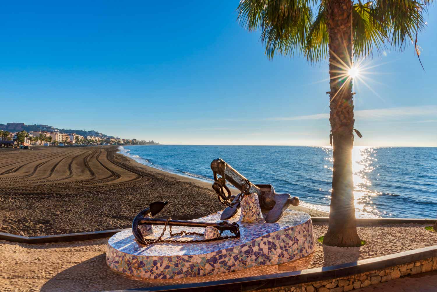 Rincon de la Victoria beach in Malaga, with a monument with ship anchors on the promenade in memory of its seafaring past - a visit to the Treasure Caves here is one of the best day trips from Malaga with kids