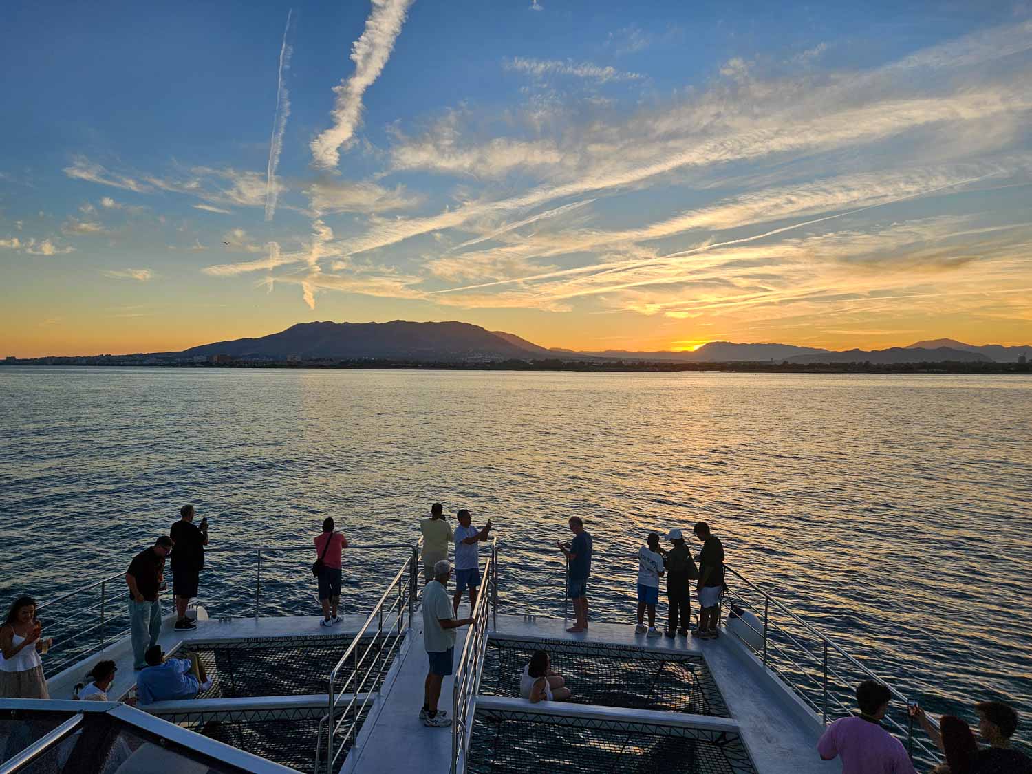 View of part of the boat and sun setting behind the headland on a sunset boat cruise - one of the best things to do in Malaga with kids