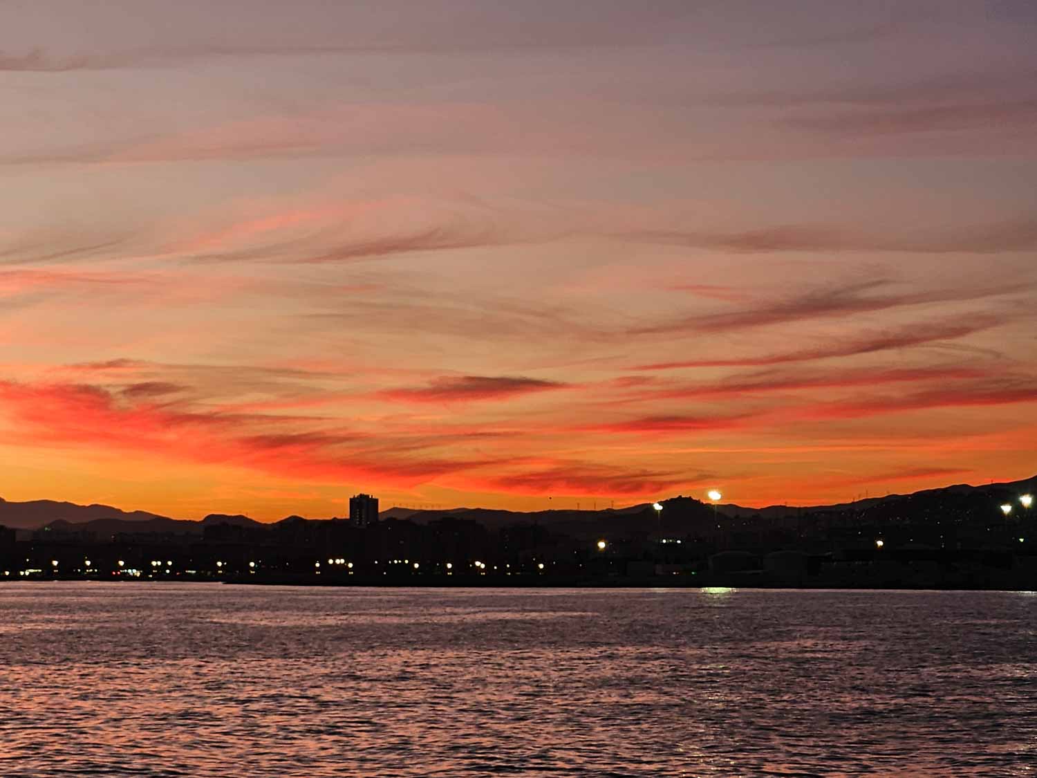 Deep orange and crimson sky seen from the water on a sunset boat cruise - one of the best things to do in Malaga with kids
