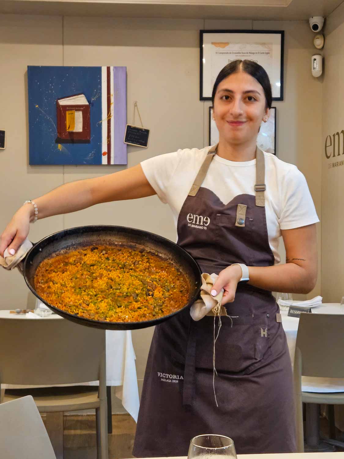 Restaurant worker holds a huge pan of paella during our tapas tour - View from the Alcazaba out across the city rooftops and cathedral of Malaga - the tours are one of the best things to do in Malaga with teens
